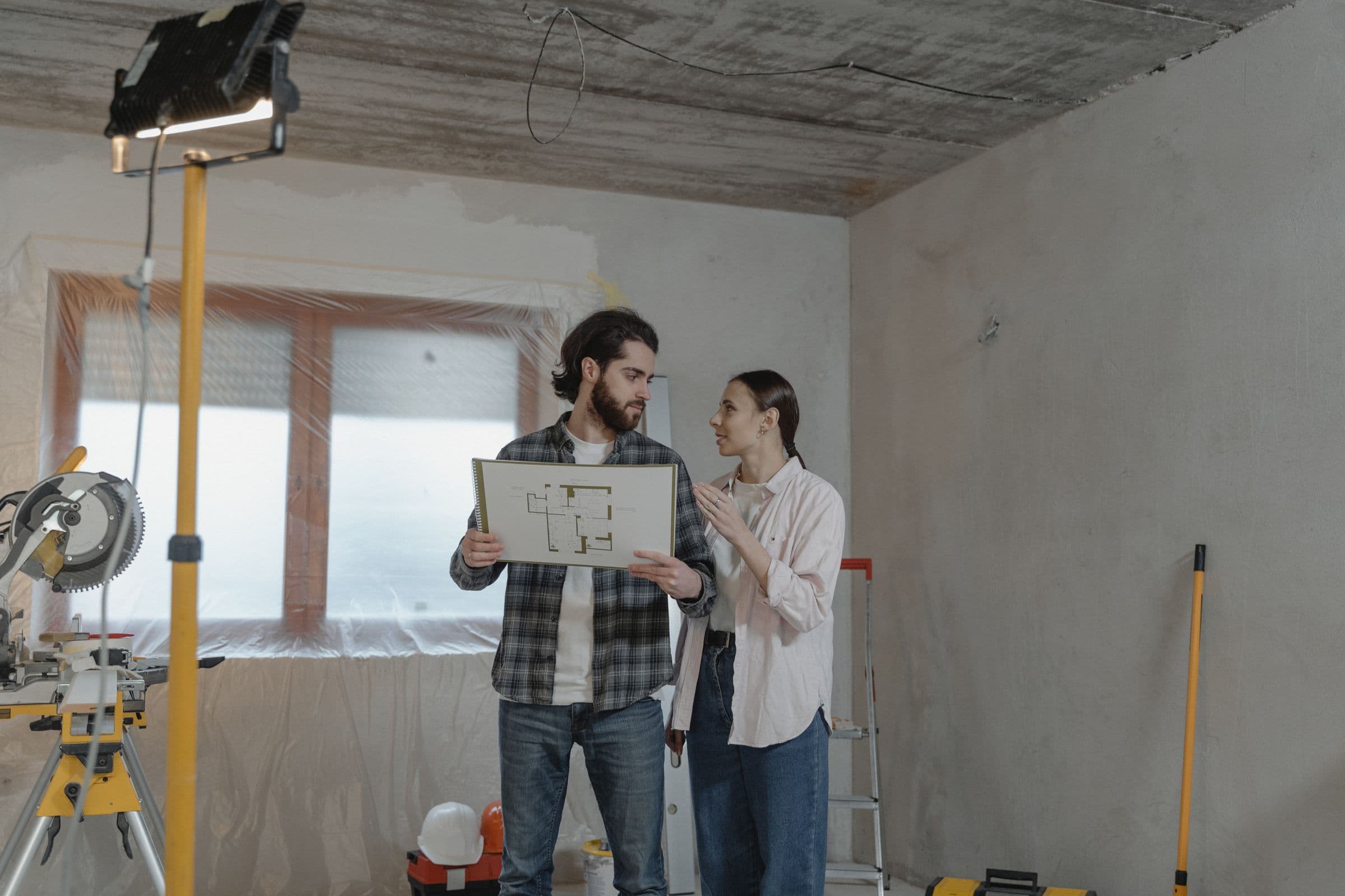 Un couple qui consulte des plans de rénovation dans une pièce en travaux